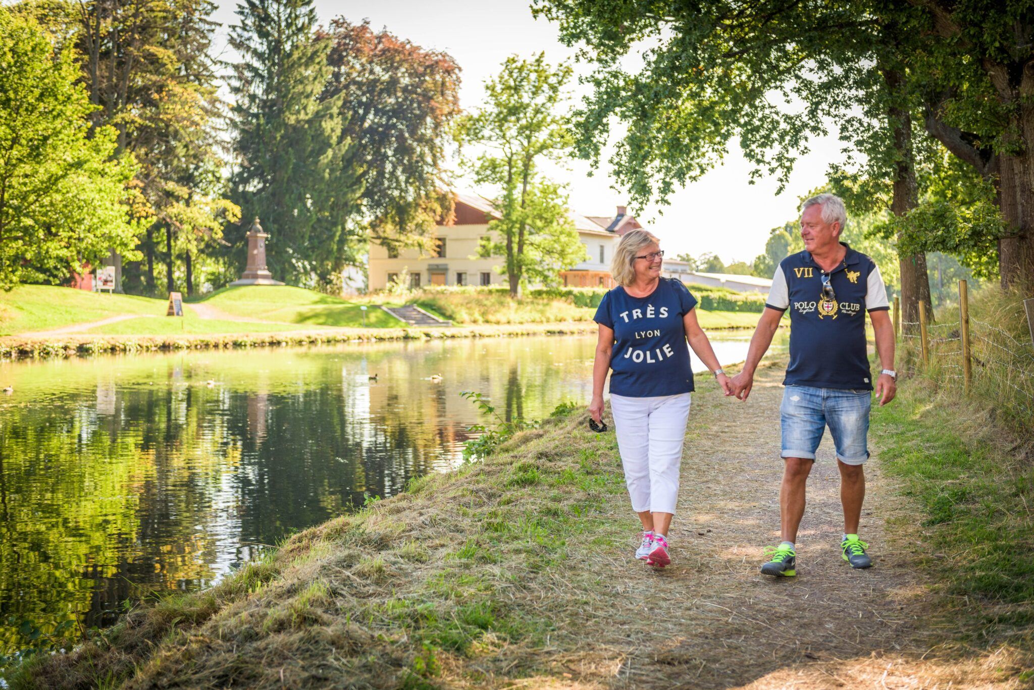 Äldre par går hand i hand längs kanalbanken