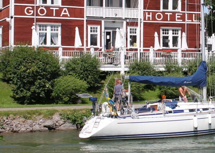 En stor vit segelbåt passerar Göta Hotell längs med Göta Kanal.