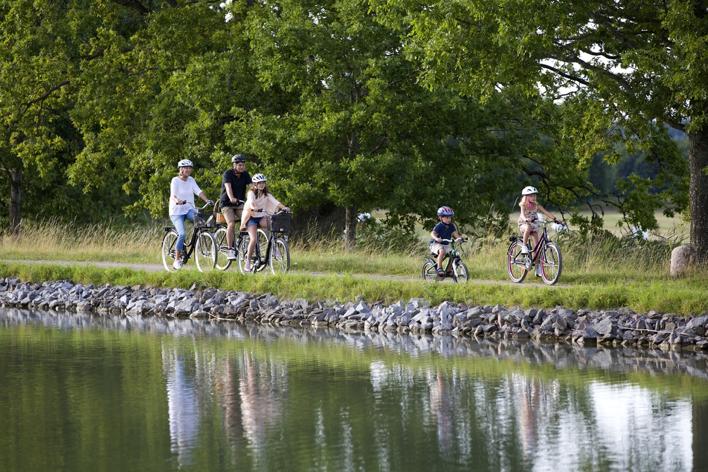 En familj med tre barn cyklar längs Göta Kanal.