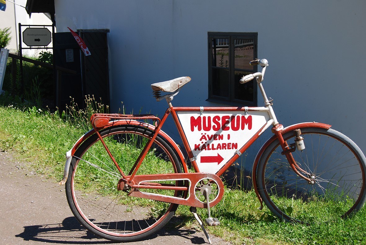 Röd cykel med skylt hängandes på ramen med texten "Museum"