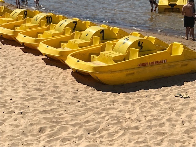 Flertalet gula trampbåtar står på en strand.