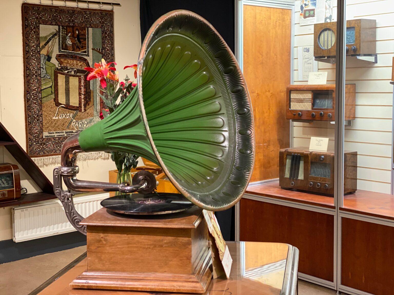 Gammal grön trattgramofon står inuti en museeilokal.