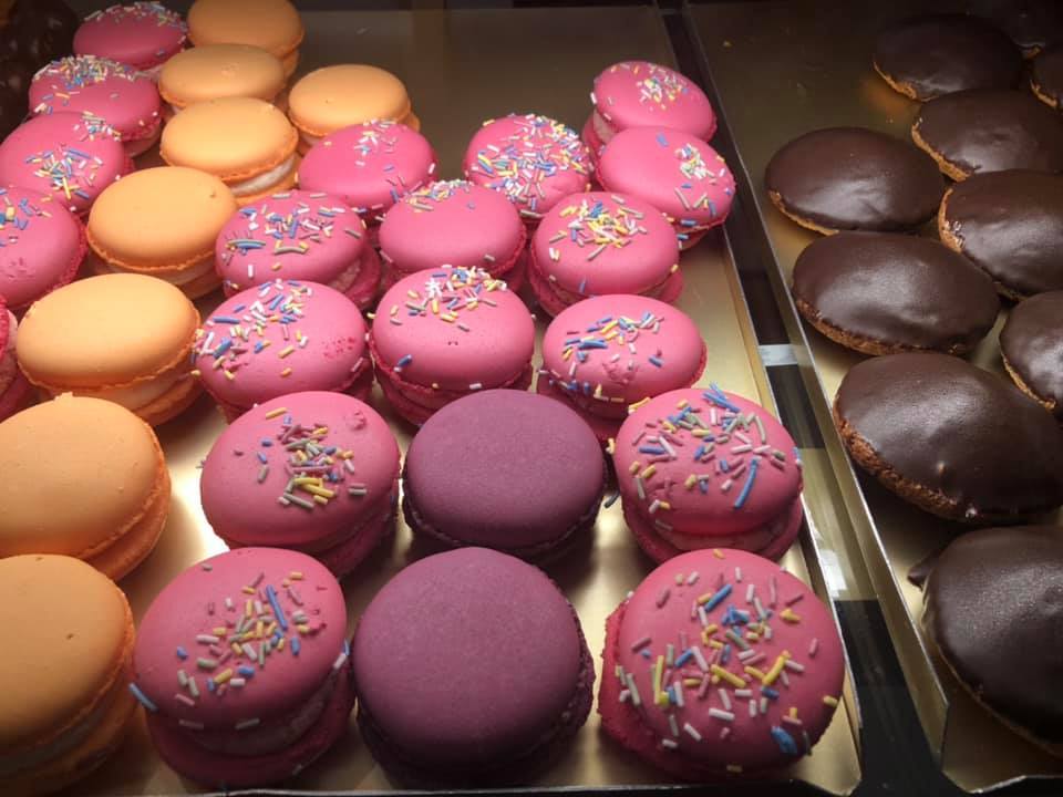 en guldfärgad plåt med rosa, gula och lila macarons, till höger chokladbeskvier.