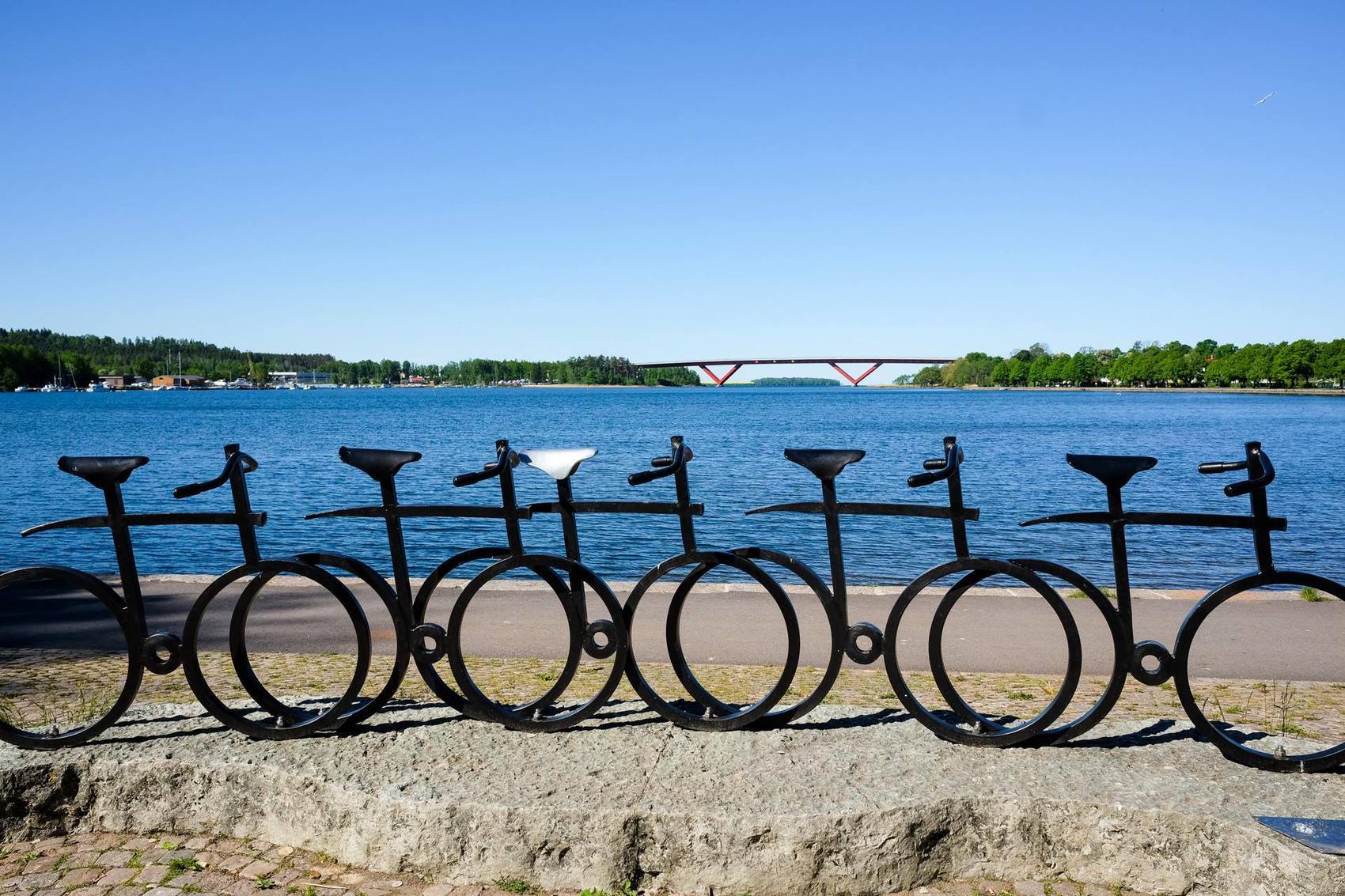 Skulptur i form av svarta cyklar framför Motalavikens blå vatten.