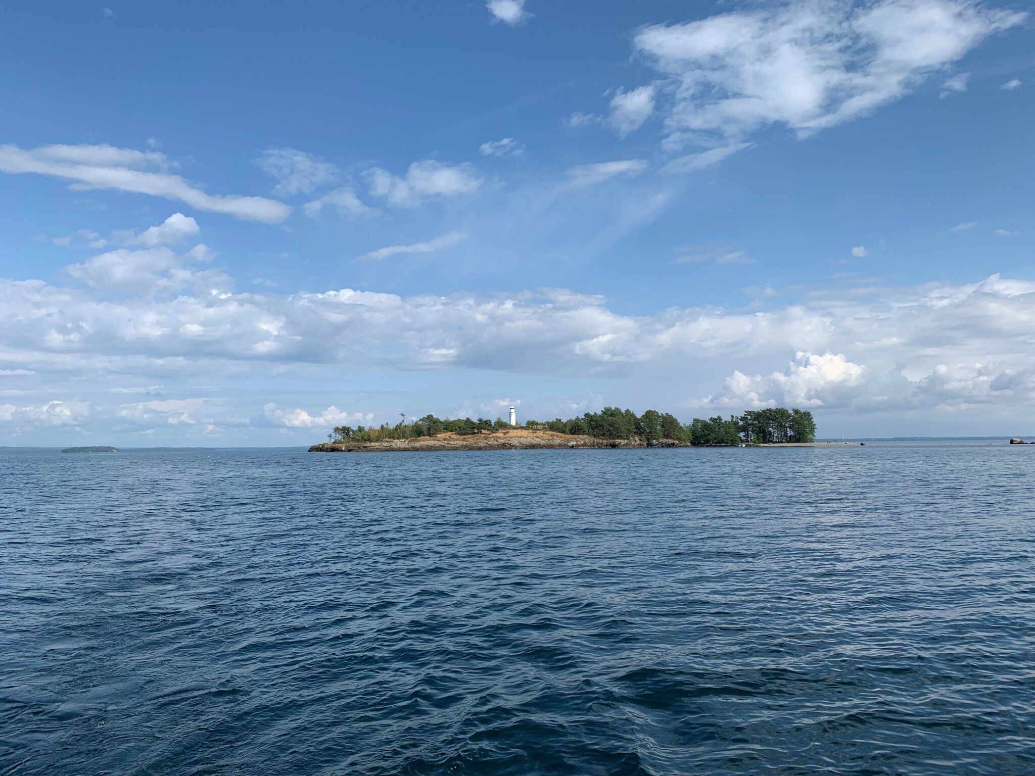 En ö omgiven av vatten och blå himmel