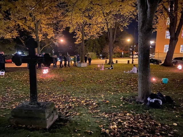 Kyrkogården utanför Motalas kyrka lyser spöklikt på kvällen. I bakgrunden skymtas en grupp människor under ett kulturevenemang.