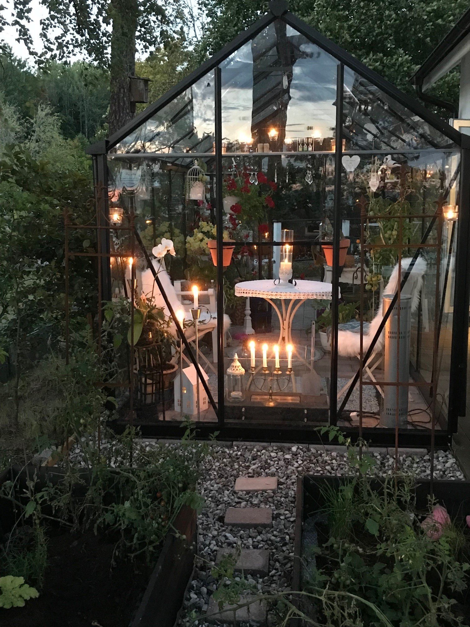 Ett svart inglasat växthus, utsmyckat med vackra detaljer och belysning som bringar ljus i kvällsmörkret.