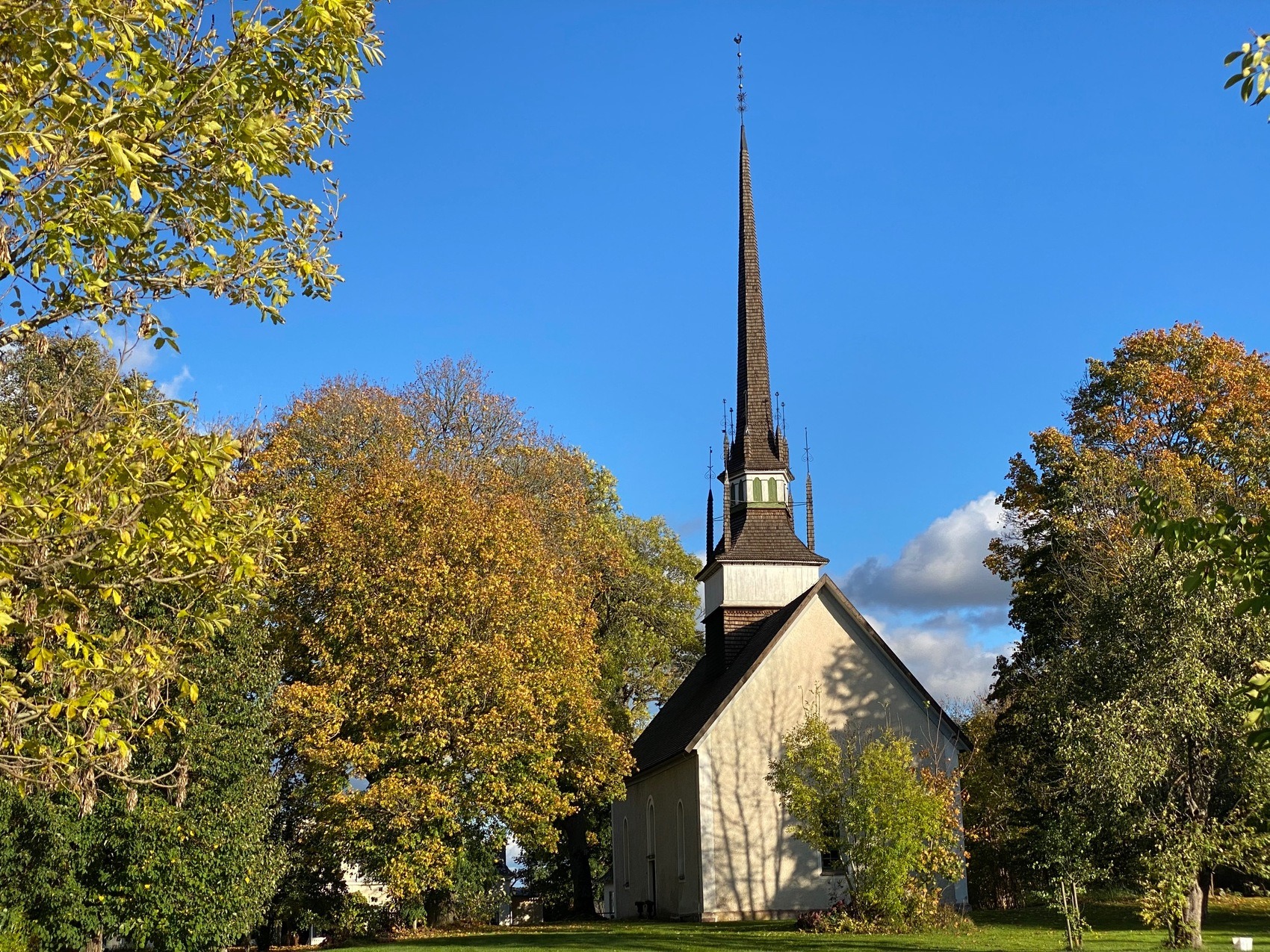 Brunnyby kyrka omgivet av gulfärgade lövträd.