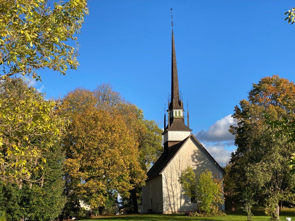 Brunneby kyrka intill höstfärgade träd.