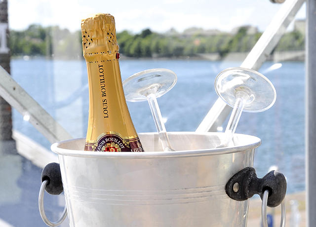 En guldig champagneflaska med glas står upp i en ishink.
