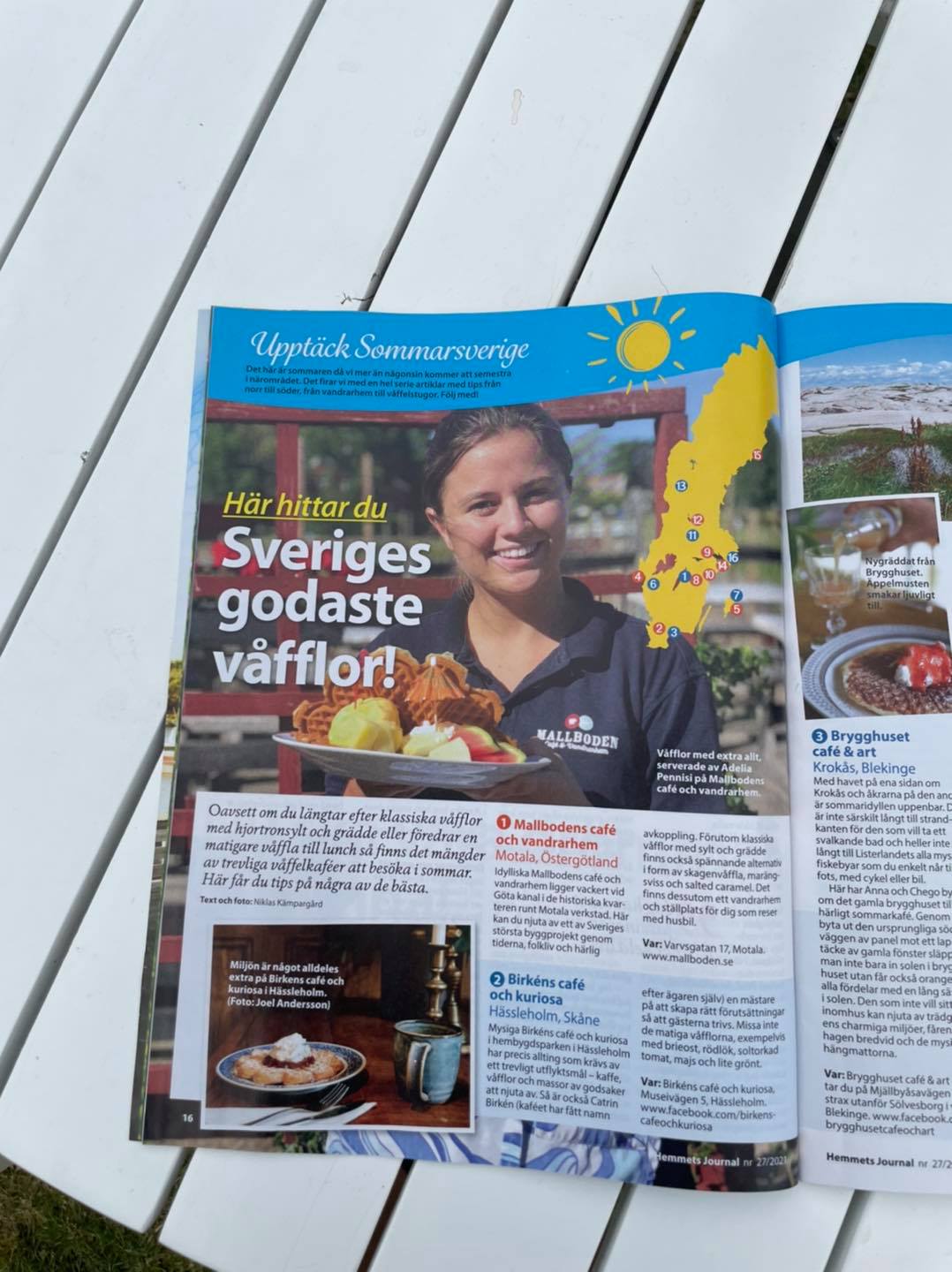 Ett magasin ligger uppslaget på ett bord med en artikel om Sveriges godaste våfflor. På bilden syns en ung tjej från Mallbodens Cafe och vandrarhem hålla upp en tallrik med våfflor.
