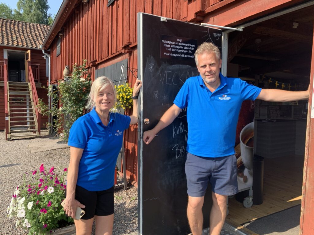 Ann Lövgren och Thomas Isacsson är ägare av Mallbodens Café och våfflor. De står i sina blå pikettröjor intill entrédörren till cafeet.