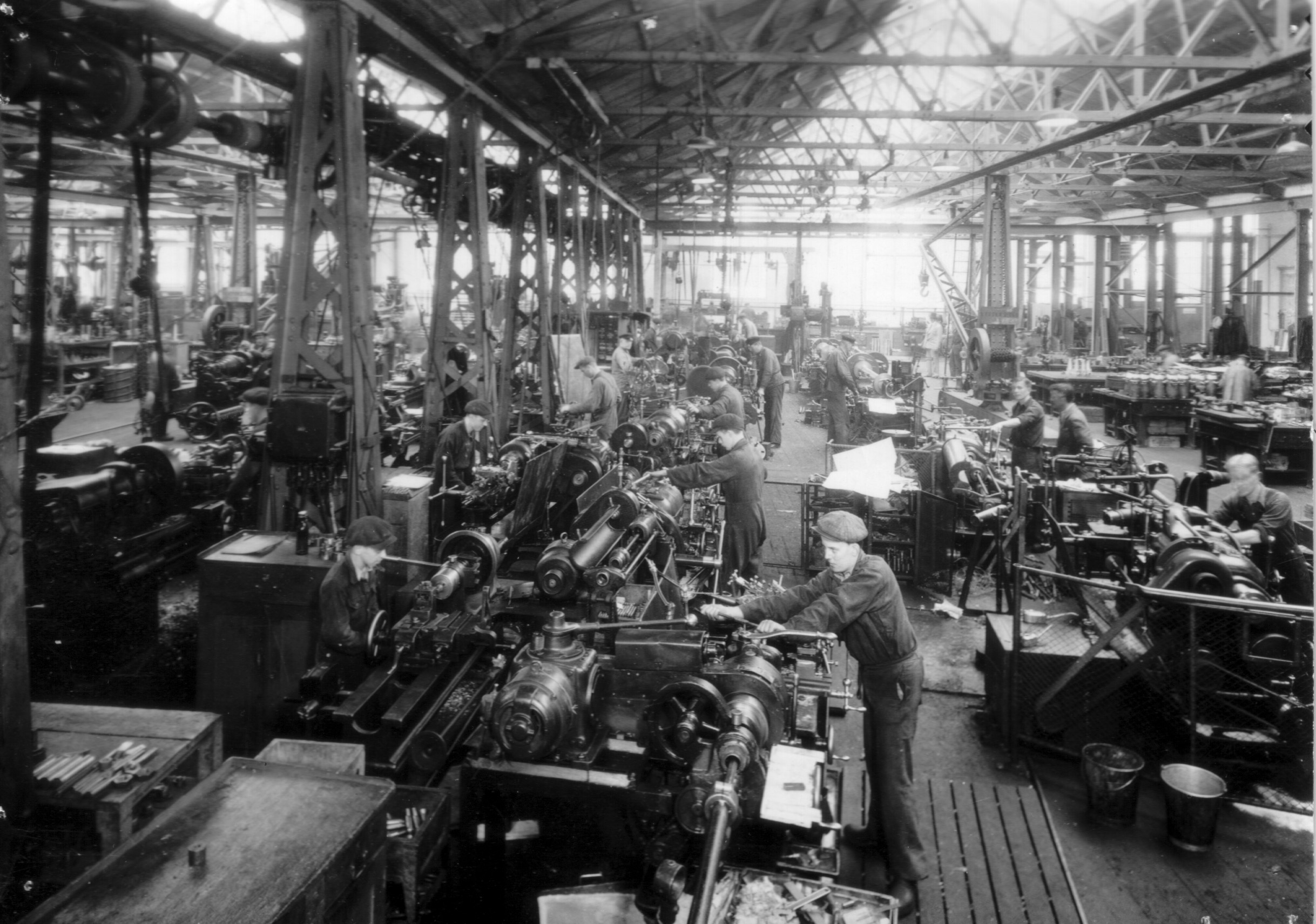 En historiskt svartvitt foto visar maskinverkstaden i Motala verkstad. Arbetsgolvet är fyllt av maskiner och personal.