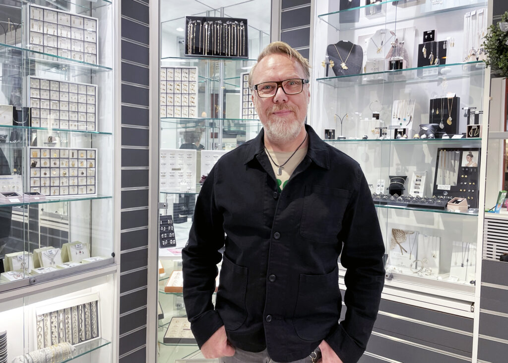 Alexander Levin, ägare av Levins, står inne i sin butik omgiven av hyllplan med vackra smycken.