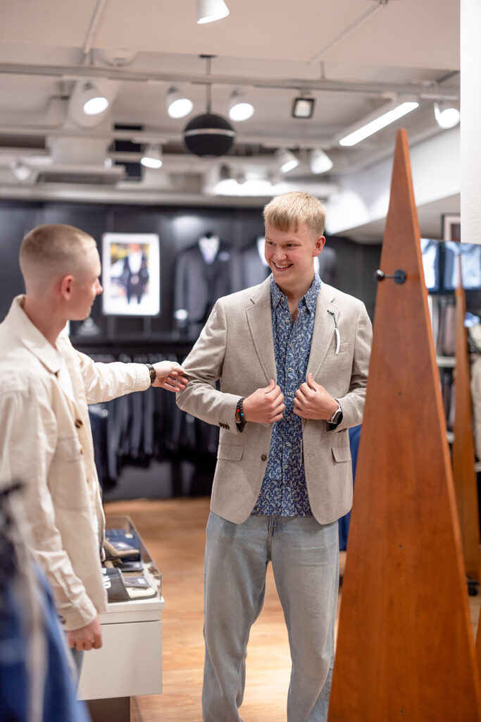 Två killar i 20-års åldern provar finkläder i en butik.