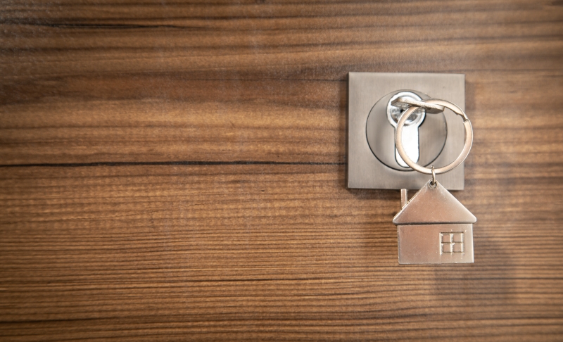 Nyckel med ett hus som nyckelring sätts in i ett dörrlås