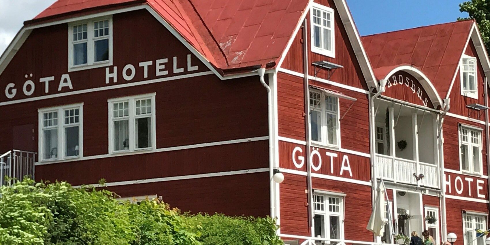 Vacker röd sekelskiftesnyggnad i trä med texten Göta Hotell på gaveln.
