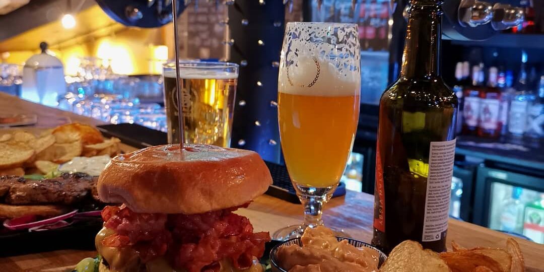 En hamburgertallrik med öl står på en bardisk